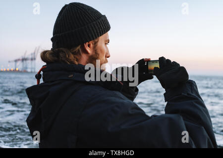 Schließen Sie die Seitenansicht eines Mannes Silhouette trägt Hut am Strand bei Sonnenuntergang, ein Bild aufnehmen Stockfoto