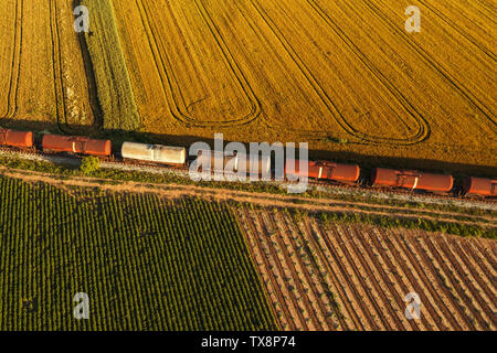 Schienengüterverkehr, Luftaufnahme von Zug passiert auf Bahnhöfen durch Feldern in Landschaft Stockfoto