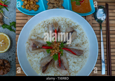 Fisch, gekochtem Reis. Congee oder conjee ist eine Art Reisbrei oder mehlsuppe beliebt in vielen asiatischen Ländern, vor allem in Ostasien, Ansicht von oben Stockfoto