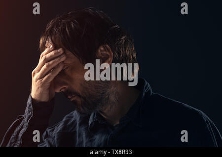 Traurig Mitte erwachsenen Mann deprimiert. Low Key Portrait von männliche Person Gefühl untröstlich. Die verzweifelten Zustand des Geistes und der geistigen Gesundheit Konzept. Stockfoto