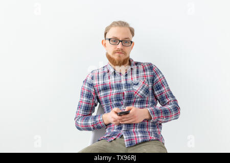 Bärtige stattlicher Mann in Plaid Shirt mit Handy auf weißem Hintergrund Stockfoto