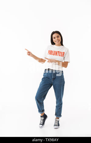Lächelnden jungen Mädchen mit Freiwilligen-T-Shirt auf weißem Hintergrund, zeigen mit dem Finger auf Platz kopieren Stockfoto