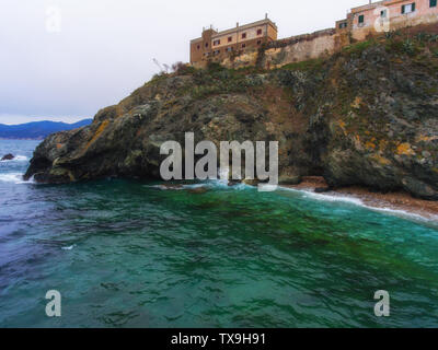 Alte Gebäude aus Stein auf den Felsen vor der Küste. Die Insel Elba. Stockfoto