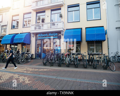 Haarlem, Niederlande - 20.August 2018: Seitenansicht des Albert Heijn niederländische Supermarktkette, 1887 in Oostzaan, Niederlande, gegründet auf Kruisstraat 10 Straße mit jungen Mann essen eine Schokolade außerhalb Stockfoto