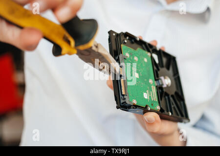 Close-up Weiblich es Computer Reparatur es Frau mit dem gelben Metall Zange schlechte Herstellung HDD Festplatte Daten Informationen zum Entfernen von SATA-Port Defekt zu beheben. Stockfoto