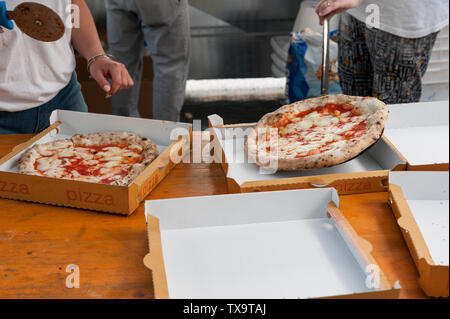 Heiße Pizza Margherita in Scheiben schneiden, fertig zum Mitnehmen - in Kartons. Stockfoto