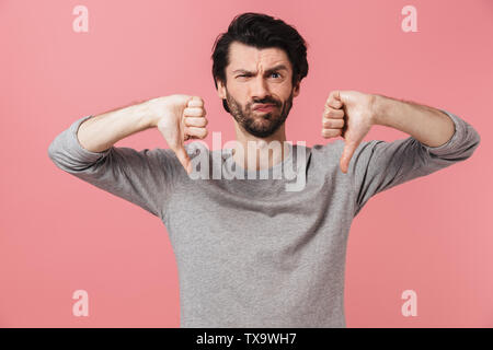 Porträt eines umgekippten bärtiger Mann stehend über rosa Hintergrund isoliert, Daumen nach unten Stockfoto