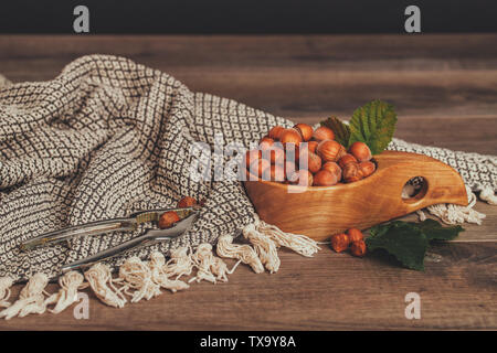 Haselnüsse mit grünen Blättern in Houten auf rustikalen braunen Hintergrund. Stockfoto