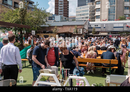 UK, London - Menschen zu essen, an einem sonnigen Tag. Essig Yard ist ein Städtischer Garten geöffnet sieben Tage die Woche, mit Ständen, Vintage Kleidung und Antiquitäten t Stockfoto