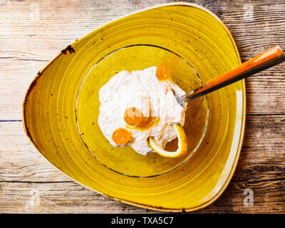 Glas Glas mit leckeren Zitrone Mousse auf gelbem Teller auf hölzernen Tisch Stockfoto