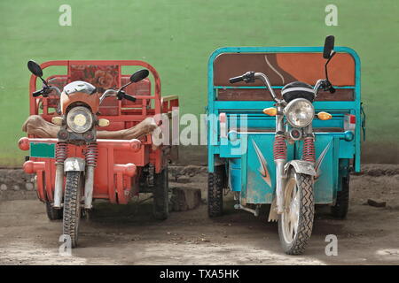 Rote und blaue Dreiräder im Viehmarktgebiet. Hotan-Xinjiang-China-0184 Stockfoto