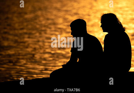 Hannover, Deutschland. 24. Juni, 2019. Zwei Männer sitzen im Licht der untergehenden Sonne am Maschsee. Credit: Hauke-Christian Dittrich/dpa/Alamy leben Nachrichten Stockfoto