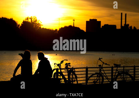 Hannover, Deutschland. 24. Juni, 2019. Zwei Männer sitzen im Licht der untergehenden Sonne am Maschsee. Credit: Hauke-Christian Dittrich/dpa/Alamy leben Nachrichten Stockfoto