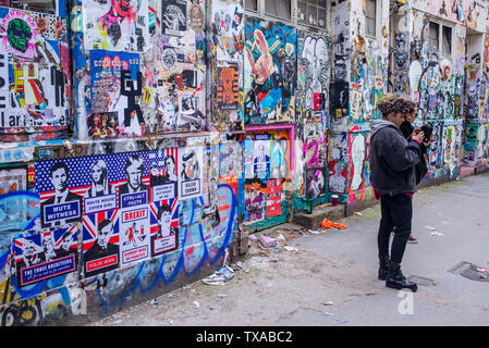 Zwei hipster junge Frauen an der Graffiti in der berühmten shoreditch Graffiti Wall suchen, Brick Lane, Shoreditch, London. Stockfoto