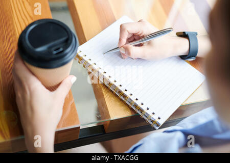 Nahaufnahme der unkenntlich Frau am Tisch und trinken Kaffee sitzen Stockfoto