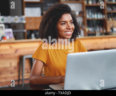 Lächelnd afrikanische Frau mit Laptop im Café Stockfoto