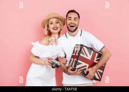 Attraktive fröhlicher junger Paare stehen zusammen über rosa Hintergrund isoliert, die zusammen reisen, Koffer Stockfoto