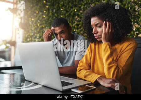 Besorgt junges Paar mit Laptop im Cafe Stockfoto
