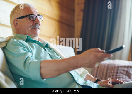 Fröhlicher älterer grauhaariger Mann in Brillen und Shirt Stockfoto