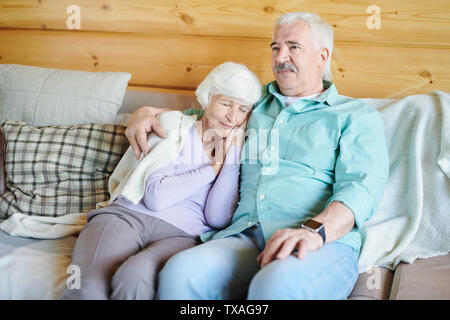 Älterer Mann in der casualwear sitzen auf der Couch und Fernsehen Programm Stockfoto