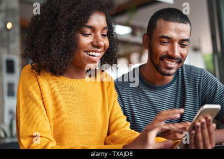 Fröhlicher junger Paare an Smartphone suchen Stockfoto