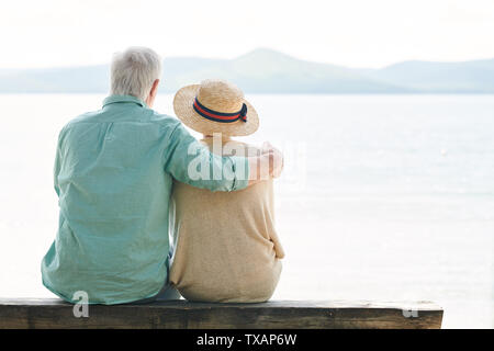 Rückansicht des heiteren senior Paar in Freizeitmode suchen am See Stockfoto