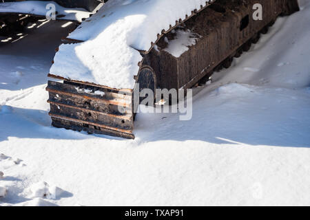 Teil von schweren industriellen kontinuierlichen Titel werfen Schatten auf Schnee. Stockfoto