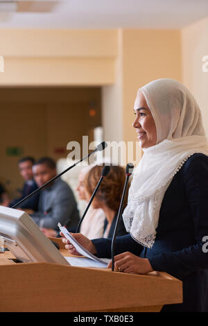 Hübsche Junge lächelnd muslimischen Frauen Lautsprecher steht die Tribüne Stockfoto
