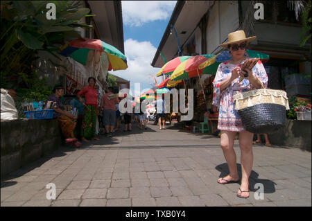 Ubud, Bali, Indonesien - 12. April 2019: Bild der weltberühmten Touristenattraktion in Ubud, der Kunstmarkt mit einem chinesischen Touristen Trinkgeld auf Ihrem Telefon Stockfoto