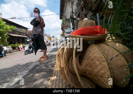 Ubud, Bali, Indonesien - 12. April 2019: Low Angle street view von Jalan Raya in Ubud mit einigen traditionellen konischen Bambus Hüte auf den Bürgersteig a festgelegt. Stockfoto