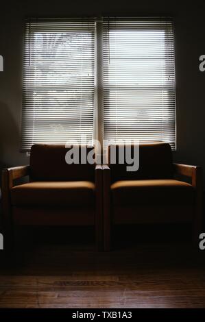 Sessel nebeneinander in einem dunklen Raum mit Ein großes Fenster Stockfoto