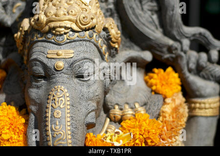 Vorderen Kopf geschossen von einem schönen Ganesha Stein Statue mit Ringelblume Blumen dekoriert und vor einem Spa Eingang in Ubud, Bali - Indonesien Stockfoto