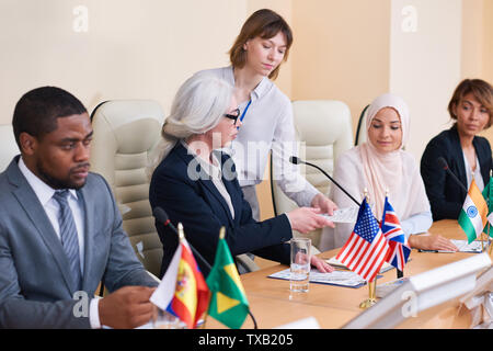 Junge Sekretärin die Unterlagen nicht der interkulturellen Delegierten Stockfoto