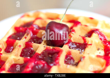 Köstliche Belgische Waffeln mit Kirsch Sirup und Chocolate Chips auf einem weißen Teller. Rot saftige Kirsche an der Oberseite Stockfoto