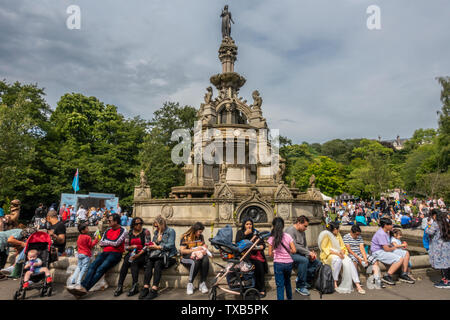 Ein multikulturelles Publikum braucht Zeit aus Glasgow Mela 2019, um den Verwalter Springbrunnen in der Mitte des Kelvingrove Park in der Stadt West End. Stockfoto