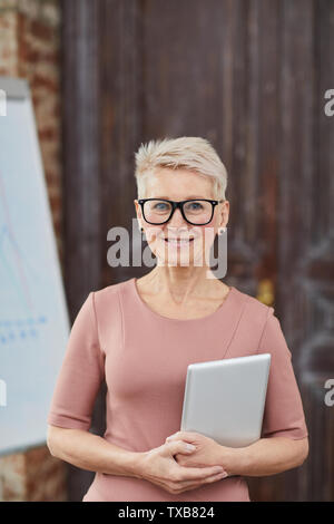 Taille bis Portrait von erfolgreichen reife Geschäftsfrau Brille fröhlich in die Kamera lächelt, während in modernen Büro posing Stockfoto
