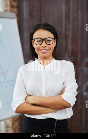 Taille bis Portrait von schönen gemischten Rennen Geschäftsfrau Brille fröhlich in die Kamera lächelt, während in modernen Büro posing Stockfoto
