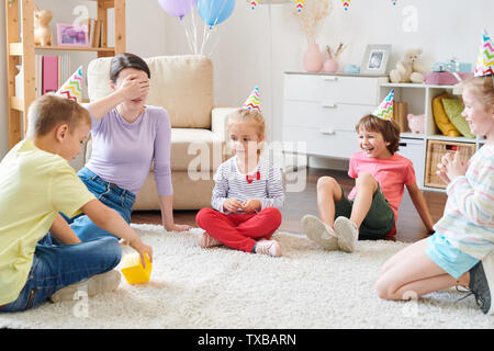 Gruppe der fröhliche kleine Kinder geburtstag Kappen im Kreis sitzen auf Teppich Stockfoto