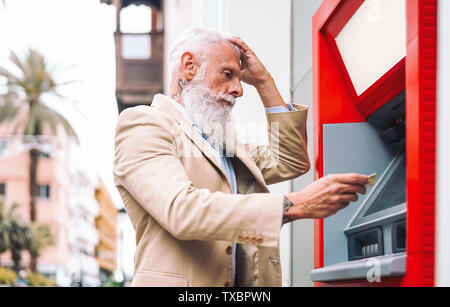 Gerne reifer Mann Geld von der Bank Geldautomaten abheben mit der ec-Karte - Ältere männliche, Bezahlung mit Kreditkarte in ATM Stockfoto