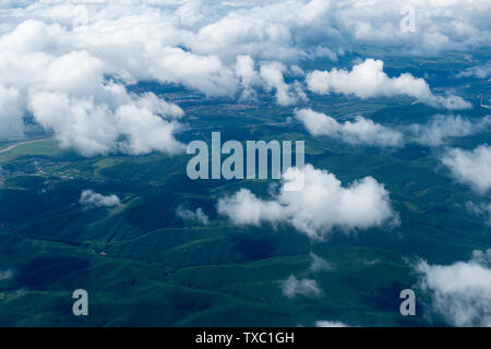 Luftaufnahme der Berge, Felder, Dörfer, Städte unter dem blauen Himmel und weißen Wolken des Heilongjiang Fluss Stockfoto