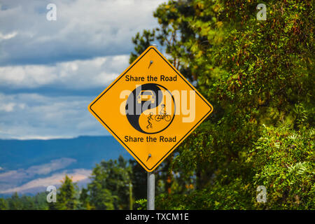 Anteil der Straße gelbes Schild auf grünem Laub und blauer Himmel. Stockfoto