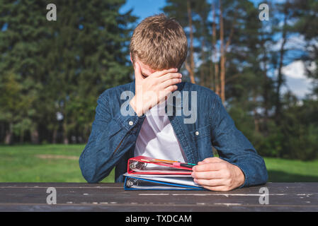 Verwirrt Teenager seine Hausaufgaben allein tun in einem Park. Stockfoto