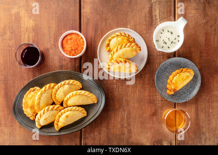 Empanadas mit Saucen und Wein, Schuß von der Oberseite in einem dunklen Holzmöbeln im Landhausstil Hintergrund mit einem Platz für Text Stockfoto