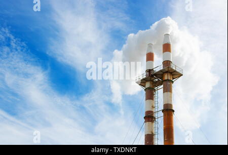 Schließen Sie herauf Bild von zwei Schornsteinen waberndem Rauch in die Atmosphäre gegen den blauen Himmel mit Kopie Raum Stockfoto