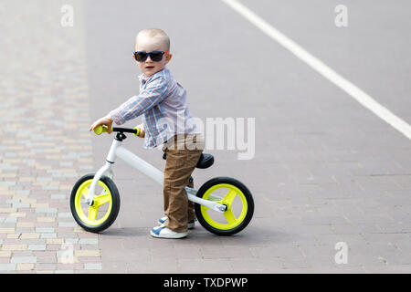 Kleine niedliche Junge lernt auf einem Fahrrad im Park zu Balance Stockfoto