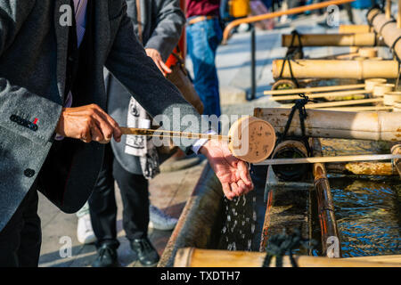 Kyoto, Japan - 21. November 2018: Touristische Ausgießen des Heiligen Wassers durch Wasser Pendelarm auf der Hand zu waschen, bevor sie in den Tempel. Stockfoto