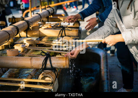 Kyoto, Japan - 21. November 2018: Touristische Ausgießen des Heiligen Wassers durch Wasser Pendelarm auf der Hand zu waschen, bevor sie in den Tempel. Stockfoto