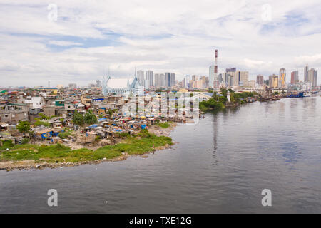 Die Slums der armen Menschen auf dem Hintergrund einer großen Stadt. Die Stadt Manila, armen und reichen Regionen. Kontrast sozialen Schichten. Stockfoto