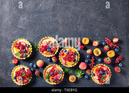 Süße französische Desserts - Torten mit Zitrone vanillesauce Creme mit Himbeeren, Aprikosen, Heidelbeeren, Erdbeeren, Johannisbeeren und frischer Minze o gekrönt Stockfoto