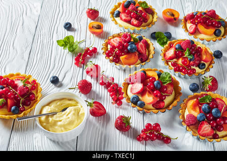In der Nähe von französischen Desserts, Torten mit Zitrone Vanillesauce creme Füllung gekrönt mit Himbeeren, Aprikosen, Heidelbeeren, Erdbeeren, Johannisbeeren und Frische Stockfoto